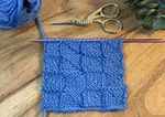A swatch of the pythagorean knit stitch pattern worked in blue wool.
