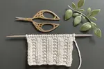 A swatch of the beaded rib knit stitch pattern worked in a light gray acrylic yarn