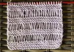 The drop stitch garter stitch swatch worked in a light lavender 100% acrylic yarn.