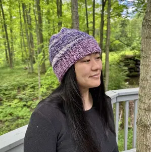 Garter stitch beannie done in varigated purple yarn and modeled on a young woman