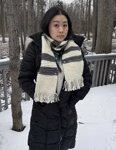 A gray and white garter stitch scarf is modeled by a young woman