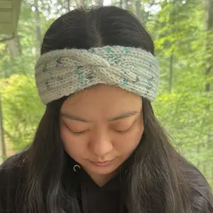 A twisted knit headband project modeled by a young woman