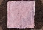 Stockinette stitch dishcloth with a garter stitch border knit in a pink cotton yarn.