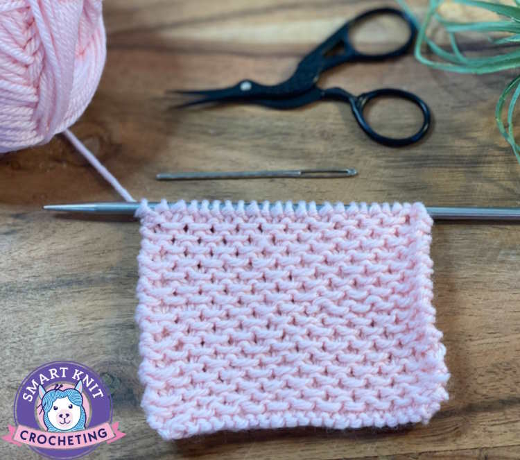 The stamen knit stitch pattern still on needles worked in 100% pink wool.