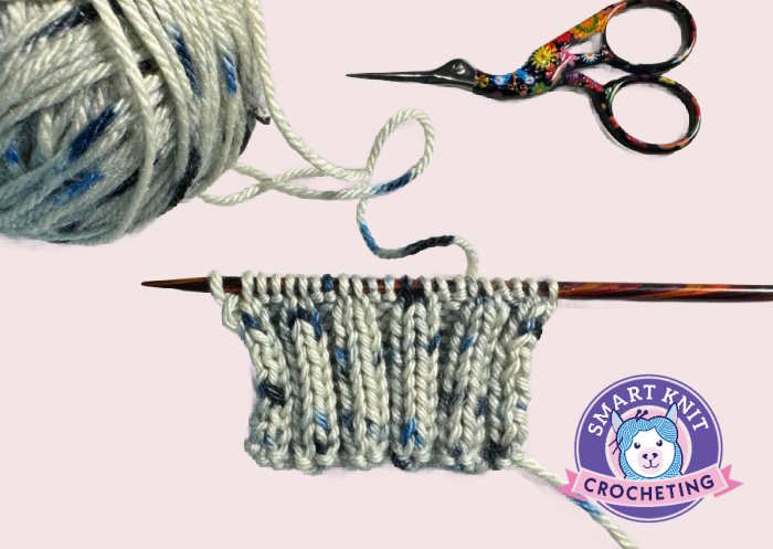 2 x 2 ribbing swatch on needles shown with a ball of yarn and scissors