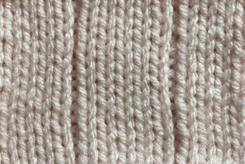 A 5x1 knit rib stitch is worked in a light pink yarn