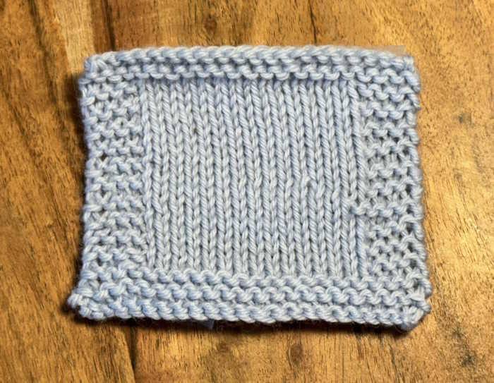 A knitted swatch made with Cascade 220 wooll worked in light blue A knitted swatch made with Cascade 220 wooll worked in light blue