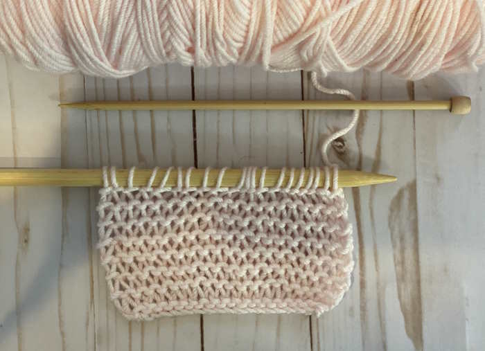 The knit condo stitch shown on needles, worked in pink