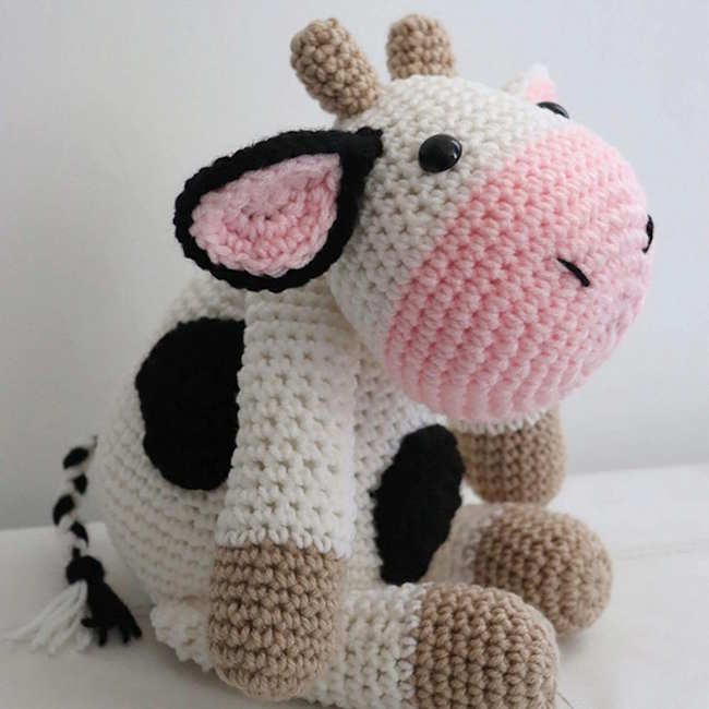 A crocheted cow toy in white brown and black