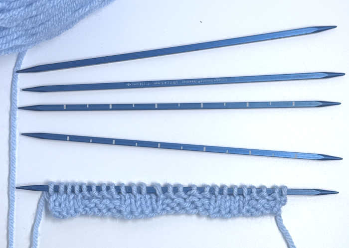 Kollage DPN holding a small knitted swatch worked in blue
