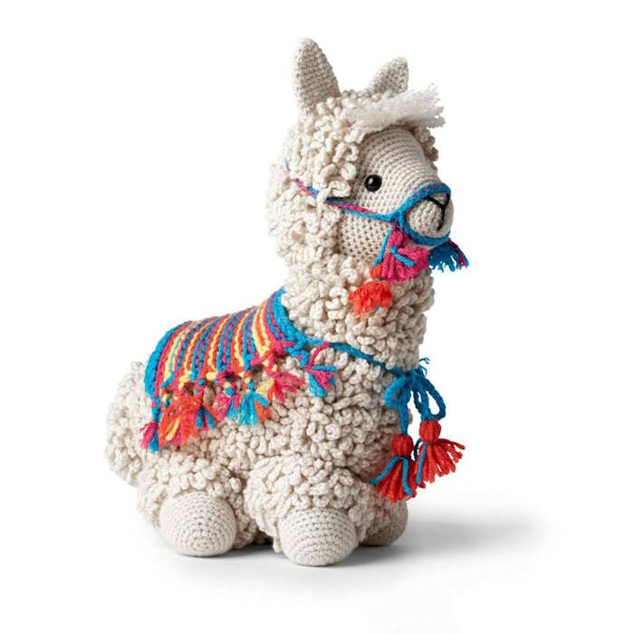 A toy llama crocheted in white with a colorful coat