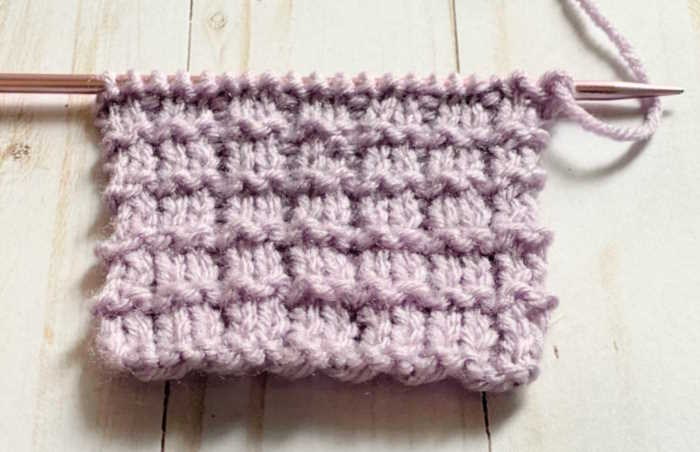 Right side facing of the Pique Knit Stitch Pattern Swatch worked in purple yarn.