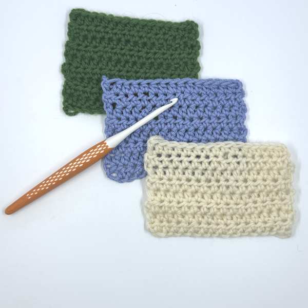 A Prym ergonomic crochet hook seen with three crochet swatches