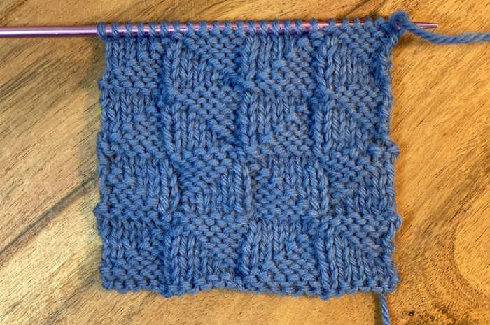 The wrong side showing of the pythagorean knit stitch pattern worked in 100% blue wool yarn.