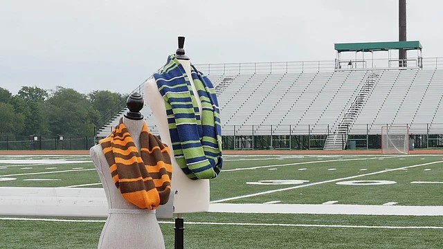 Two scoreboard cowls on maniquins in front of a football field