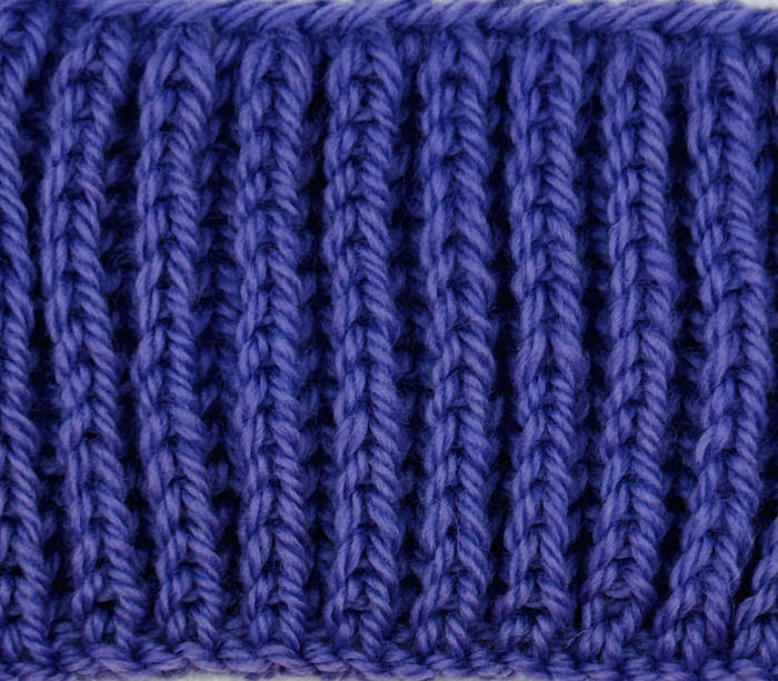 A swatch of the Shaker Rib Stitch (aka Half-Fisherman's Rib worked in purple-blue yarn.
