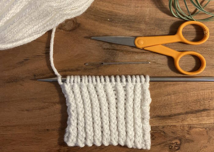 Twisted Rib Knit Stitch on needles, worked in white acrylic yarn. Twisted Rib Knit Stitch on needles, worked in white acrylic yarn.