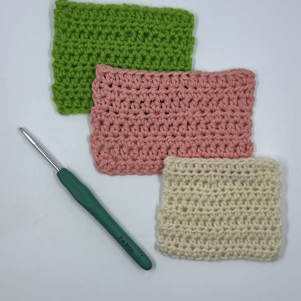 A Yarniss ergonomic crochet hook used to make three crocheted swatches