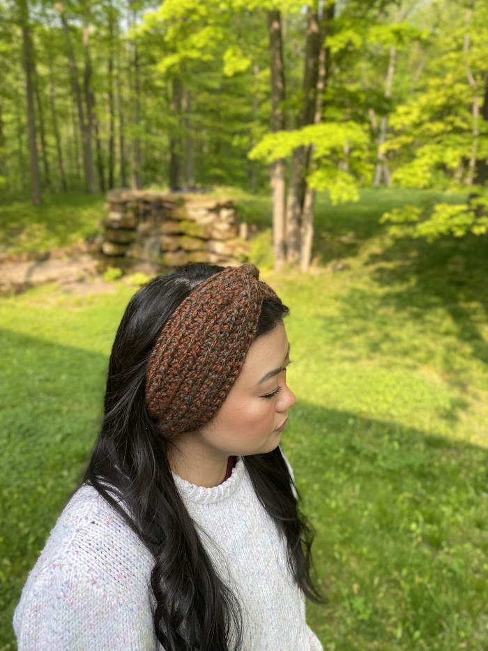 A twisted headband created with alpaca yarn is modeled with an Asian woman