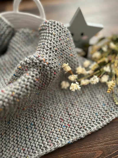 Baby blanket kit by Lion Brand showing the finished baby blanket