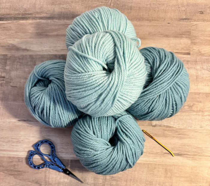 A few balls of yarn shown with scissors and a tapestry needle A few balls of yarn shown with scissors and a tapestry needle