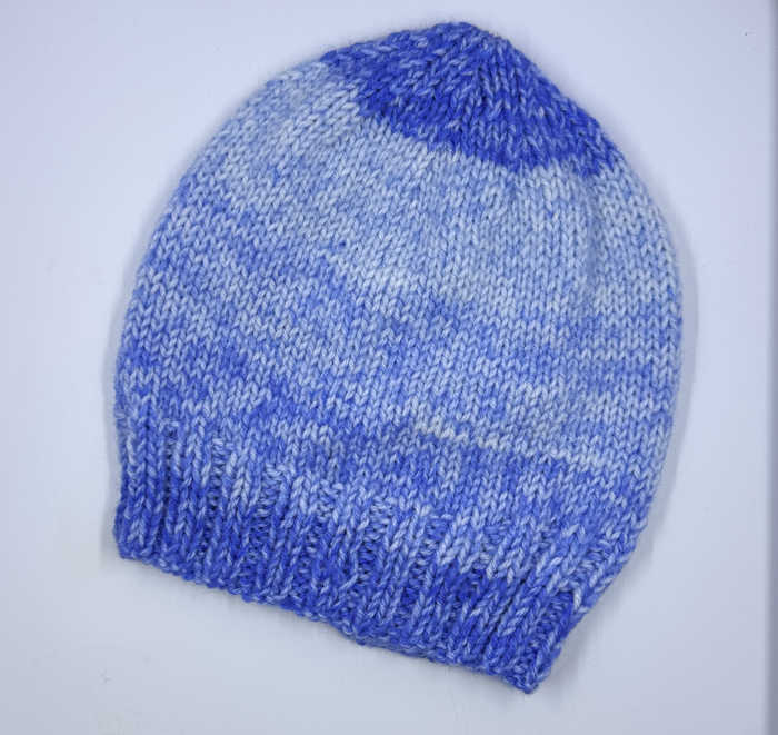 A beannie worked flat with blue varigated yarn