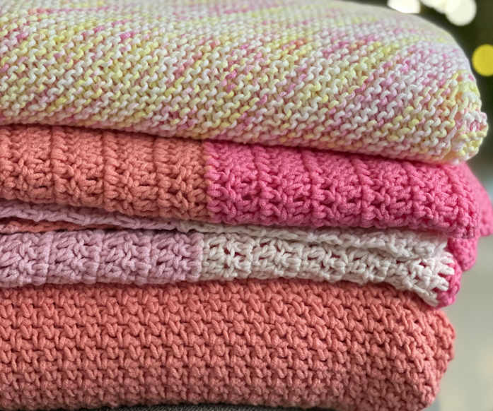 A pile of four knit blankets in various yarns and colors A pile of four knit blankets in various yarns and colors