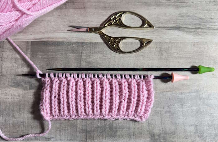A swatch of Brioche knit stitch worked in pink wool