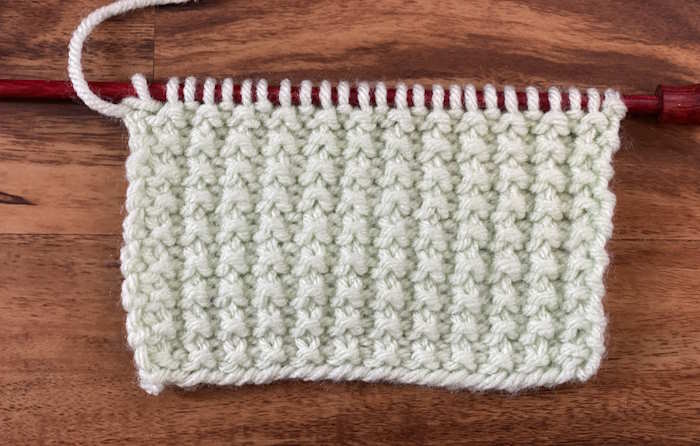 The wrong side of the broken rib knit stitch worked in green