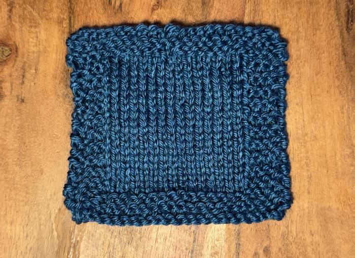 A knitted swatch worked in blue Caron Simply soft yarn