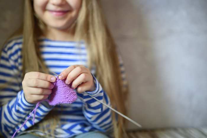 A young girl is learning to  knit