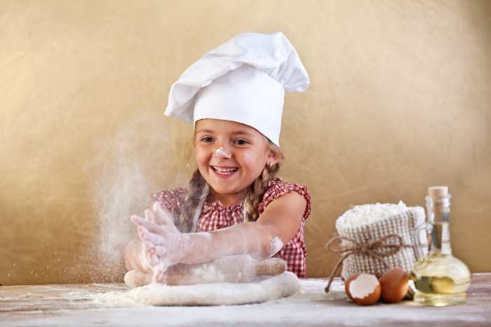 A young girl is learning to cook