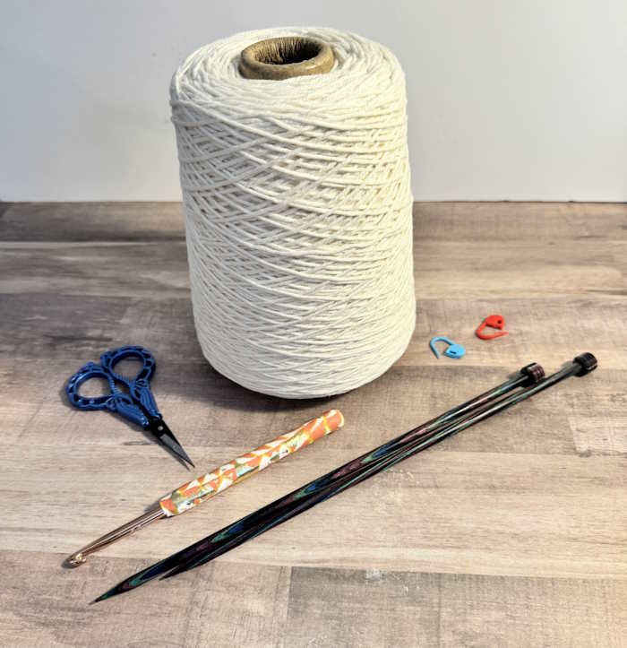 Cones and Tubes A cone of white yarn is shown with needles, a hook, and scissors