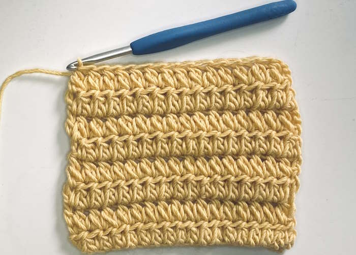 Crochet fork stitch worked in 100 % wool in a gold color