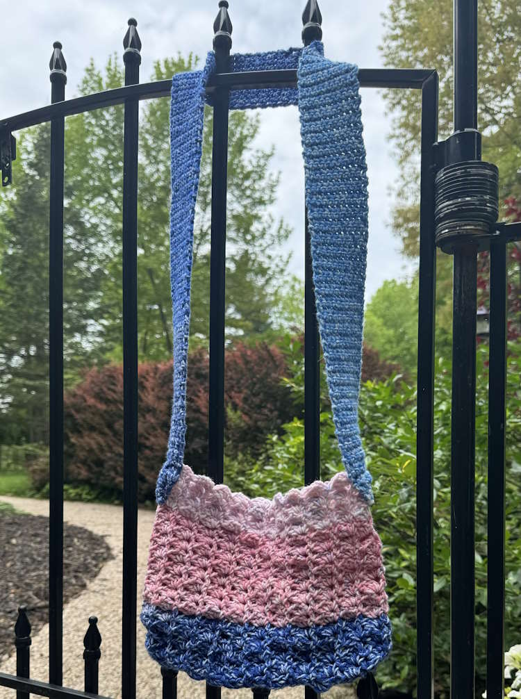 The crochet hatch stitch crossbody bag hanging on a gate