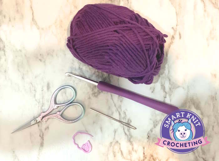 Supplies needed to make the crochet parquet stitch including purple yarn, scissors, needle, hook and stitch marker Supplies needed to make the crochet parquet stitch including purple yarn, scissors, needle, hook and stitch marker