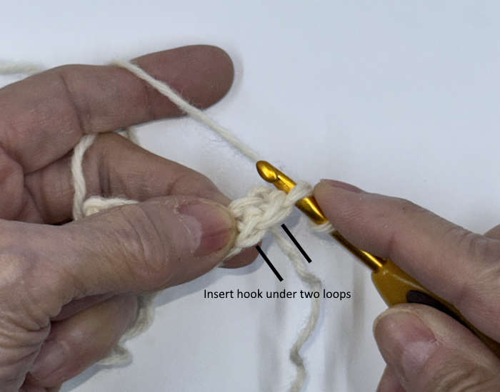 Close-up of crochet stitches showing the two top loops where the second row is worked