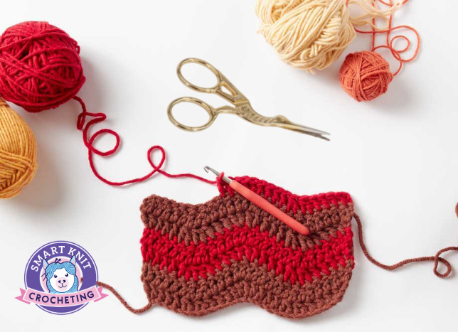 A swatch of crochet shown with balls of yarn and a pair of scissors