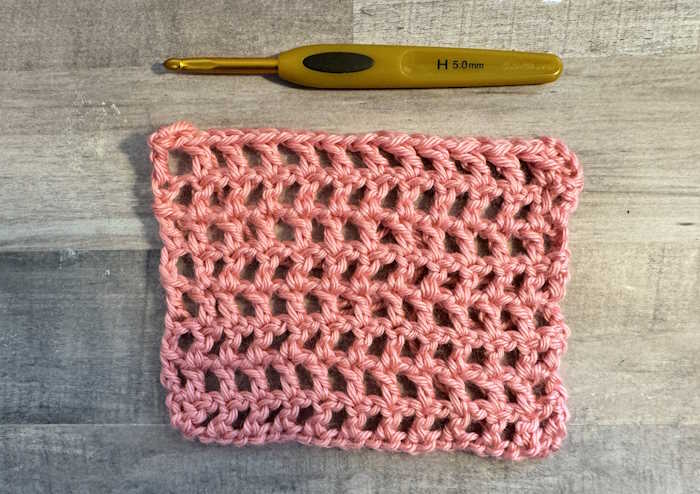 The double crochet mesh stitch swatch worked in pink acrylic yarn
