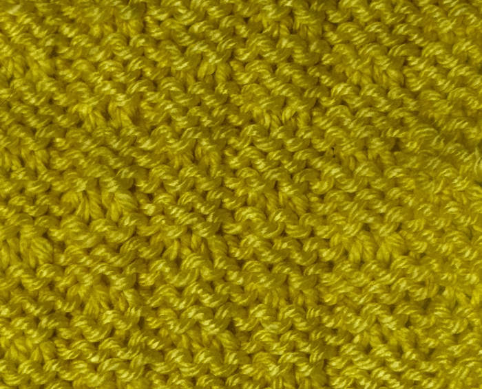 The wrong side showing of the knit double fleck stitch worked in yellow.