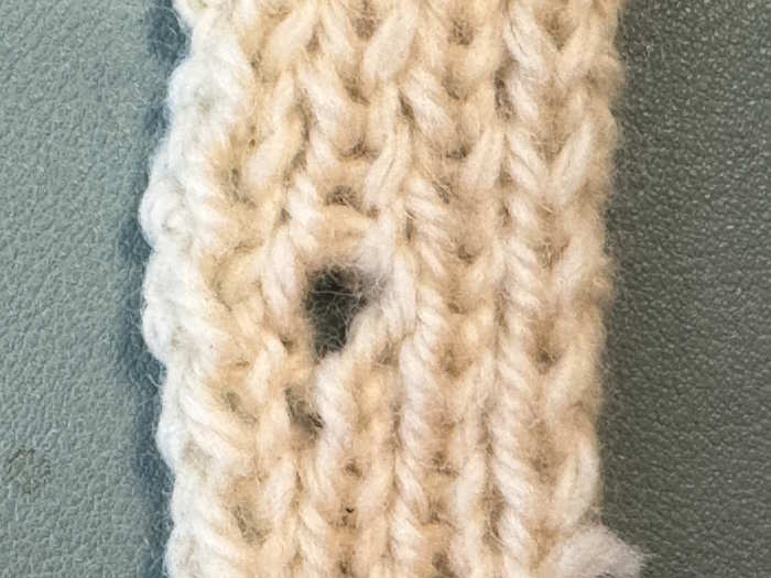 A small knit swatch showing where an eyelet or yarnover buttonhole was made. 
