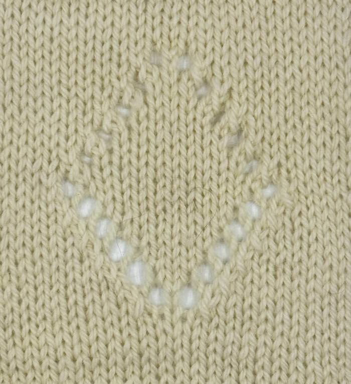 A knitted swatch in beige showing eyelets