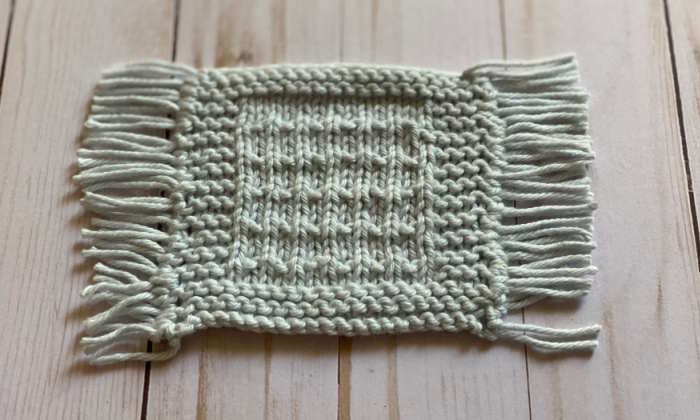 A fringed coaster made with the knit fleck stitch A fringed coaster made with the knit fleck stitch