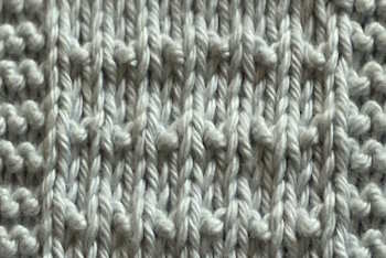 Fleck knit stitch pattern worked in an off white cotton yarn.