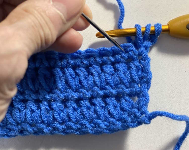 Step by step tutorial of the fork half double crochet showing where to insert the hook for the other part of the stitch.
