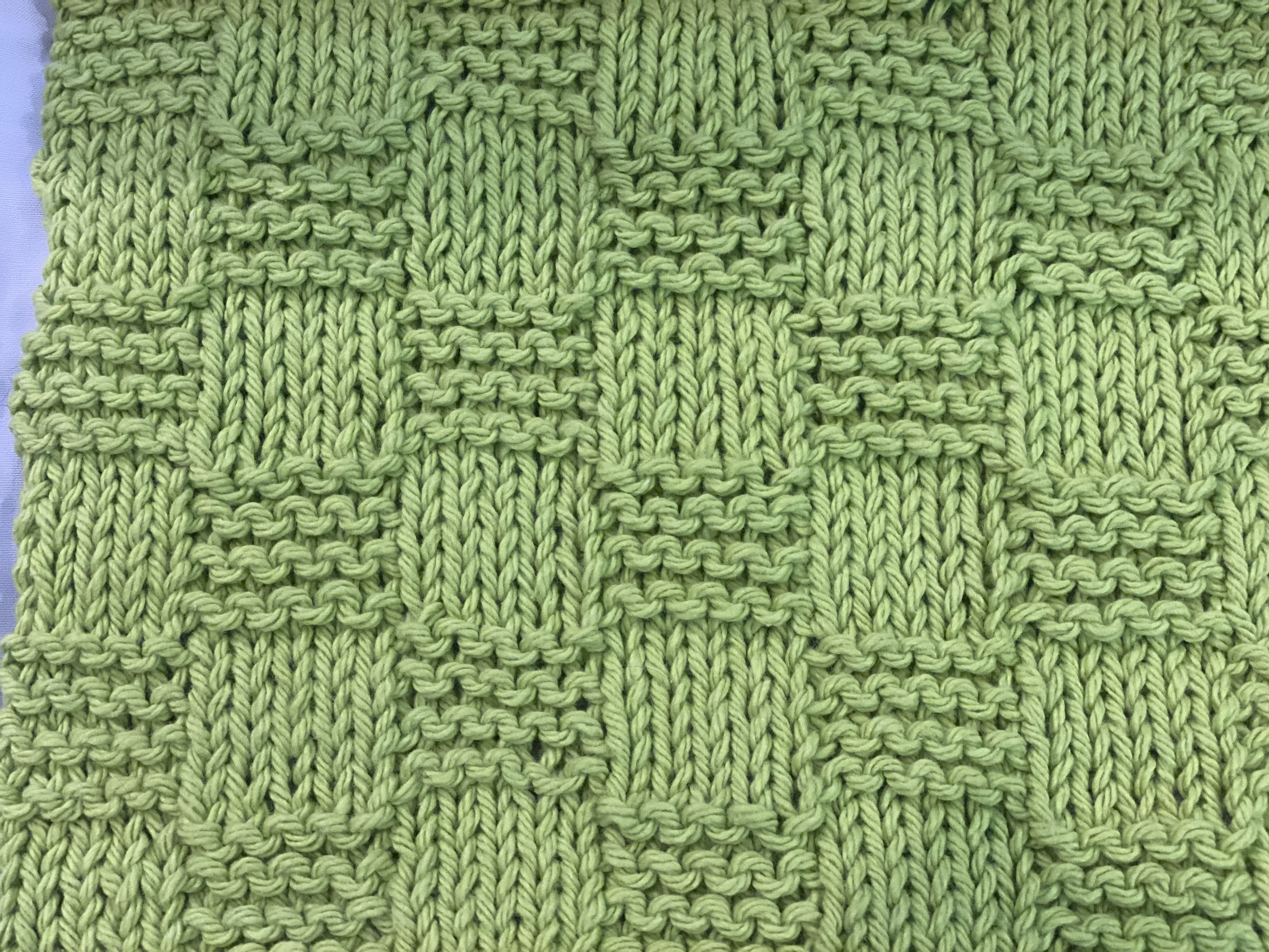 The garter checkerboard stitch shown on the right side of the fabric in green The garter checkerboard stitch shown on the right side of the fabric in green