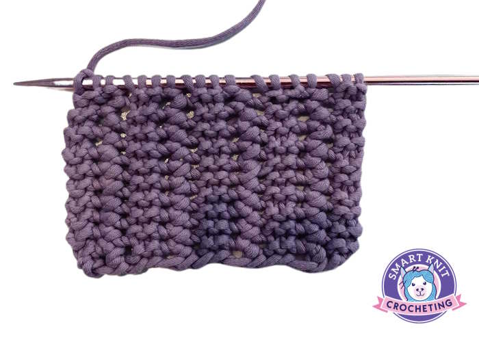 A swatch of the garter lace stitch worked in purple yarn. A swatch of the garter lace stitch worked in purple yarn.