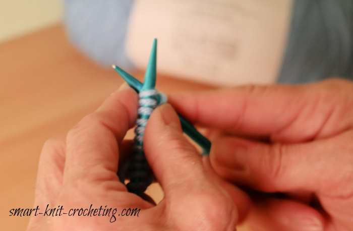 The Garter Stitch, step-by-step instructions. Shown are a pair of blue knitting needles beginning to be used in the garter stitch.