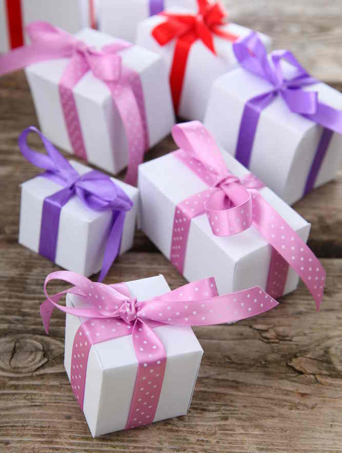 An assortment of small gift wrapped boxes in pink and purple ribbon