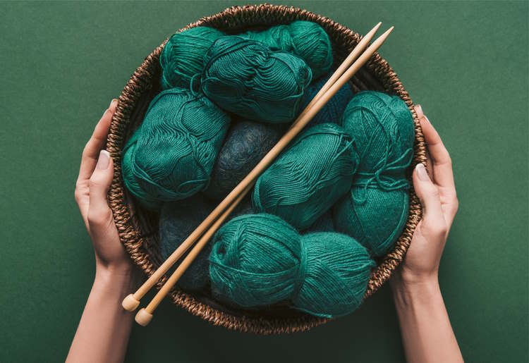A basket of green yarns with a pair of knitting needles A basket of green yarns with a pair of knitting needles